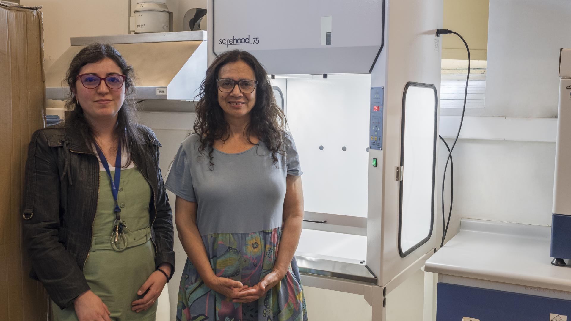 Bernardita Ladrón de Guevara, directora CNCR y Rosalía Astorga, jefa de la UCC posan junto a la nueva campana de extracción de alta tecnología para el manejo seguro de químicos volátiles y material particulado (Quiroz, M. 2025. Archivo CNCR).