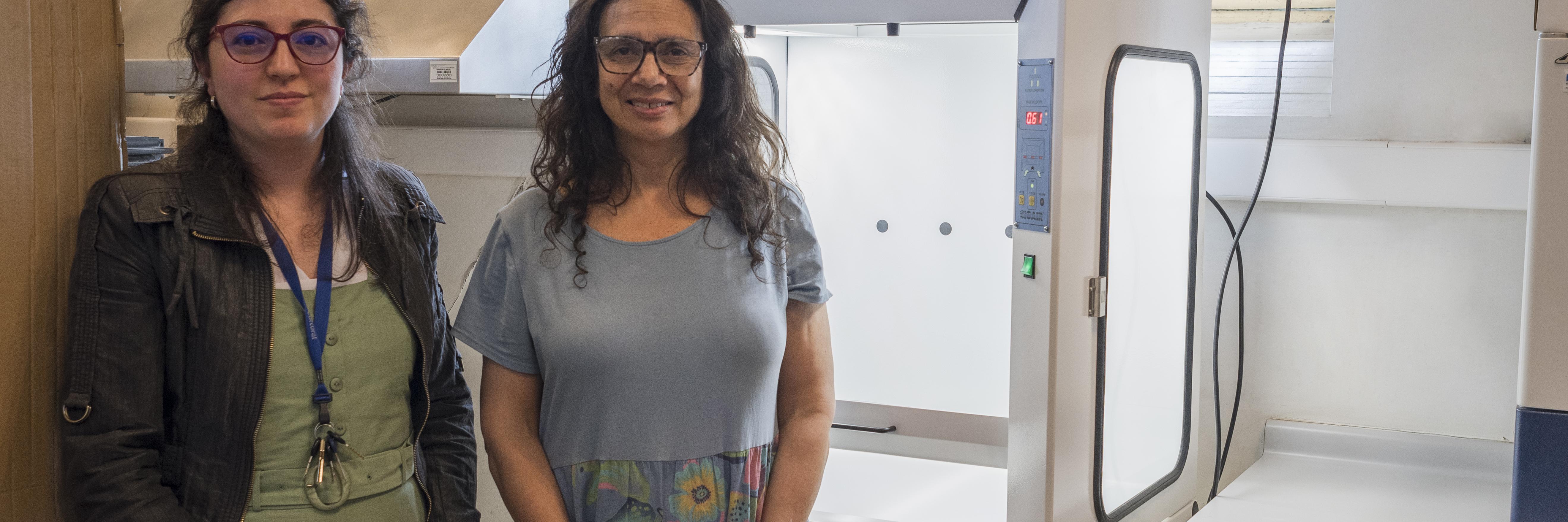 Bernardita Ladrón de Guevara, directora CNCR y Rosalía Astorga, jefa de la UCC posan junto a la nueva campana de extracción de alta tecnología para el manejo seguro de químicos volátiles y material particulado (Quiroz, M. 2025. Archivo CNCR).