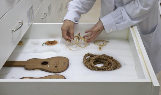 Manos disponen piezas de fibras naturales dentro de un cajón de conservación.