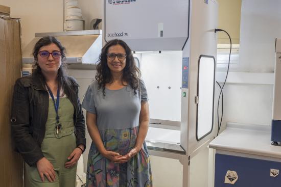 Bernardita Ladrón de Guevara, directora CNCR y Rosalía Astorga, jefa de la UCC posan junto a la nueva campana de extracción de alta tecnología para el manejo seguro de químicos volátiles y material particulado (Quiroz, M. 2025. Archivo CNCR).