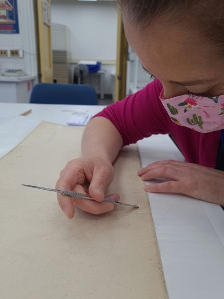 Figura 31. Proceso de eliminación de cinta adhesiva de papel desde el reverso del sismograma núm.  28 del terremoto de 1960 (Fotografía: Hortuvia Atenas, V. 2021. 2021. Archivo CNCR. UPGD886.32). upgd886.32.jpg.jpg