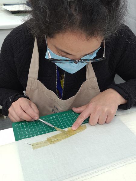 Figura 28. Retiro de cinta adhesiva en sismograma núm.  25 del terremoto de 1960 (Fotografía: Hortuvia Atenas, V. 2021. Archivo CNCR. UPGD886.40). upgd886.40.jpg